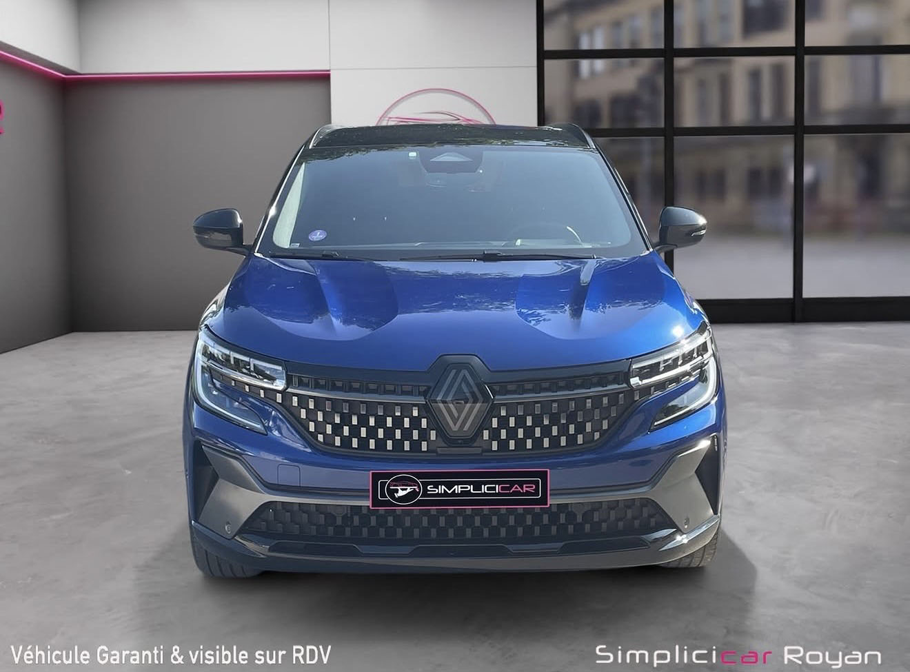 Renault Austral bleu de face dans un showroom, avant traitement